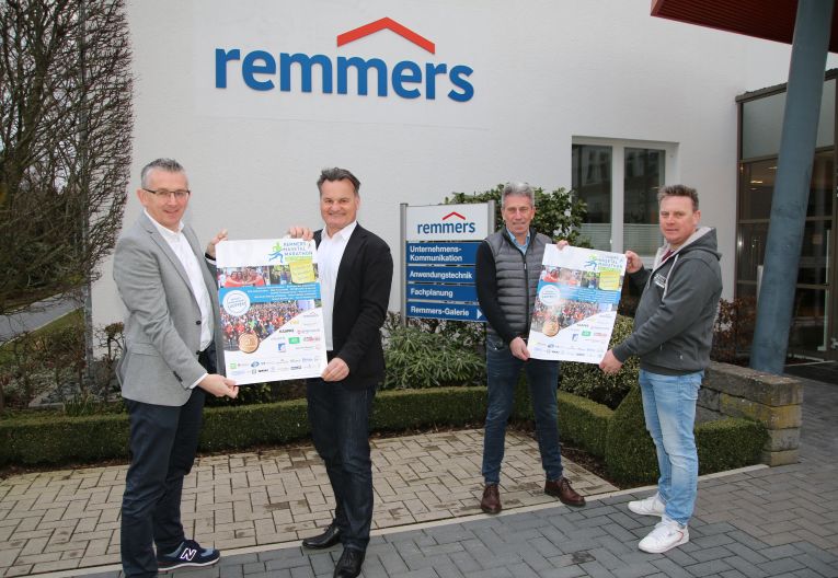 Remmers-Hasetal-Marathon Gruppenbild vier Personen mit Plakaten vor Remmers Gebäude